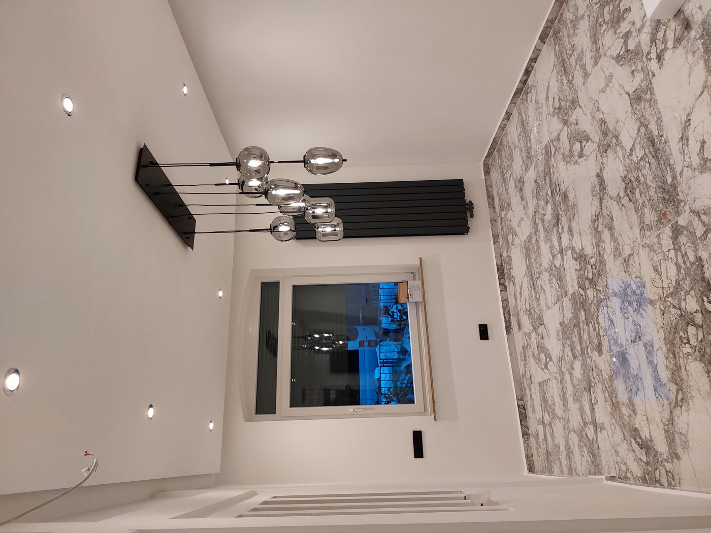 Modernes Wohnzimmer mit Marmorboden, schwarzem Designheizkörper und LED-Pendelleuchten